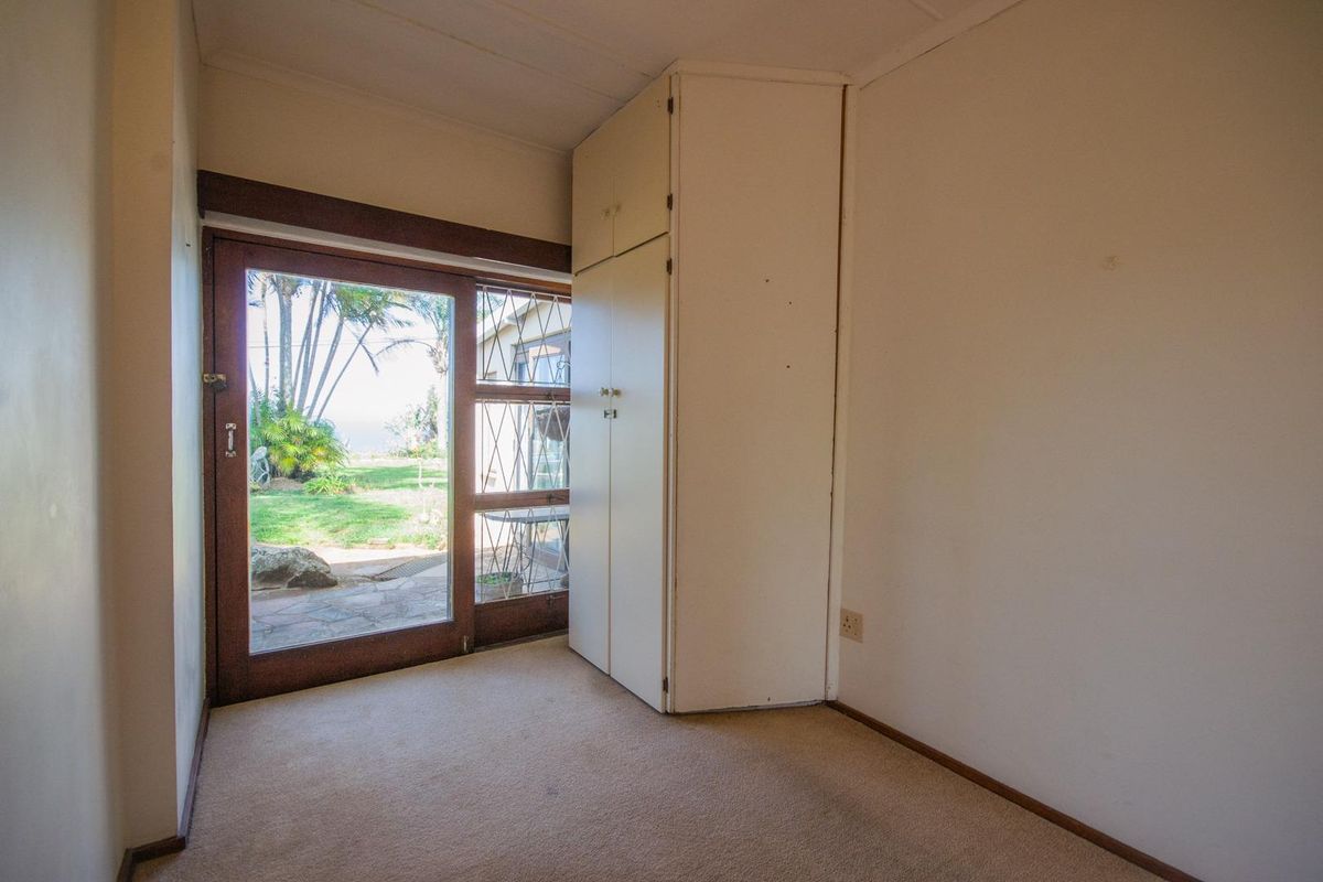 A bedroom featuring built-in storage cabinetry and a sliding glass door providing direct access to the rear garden.