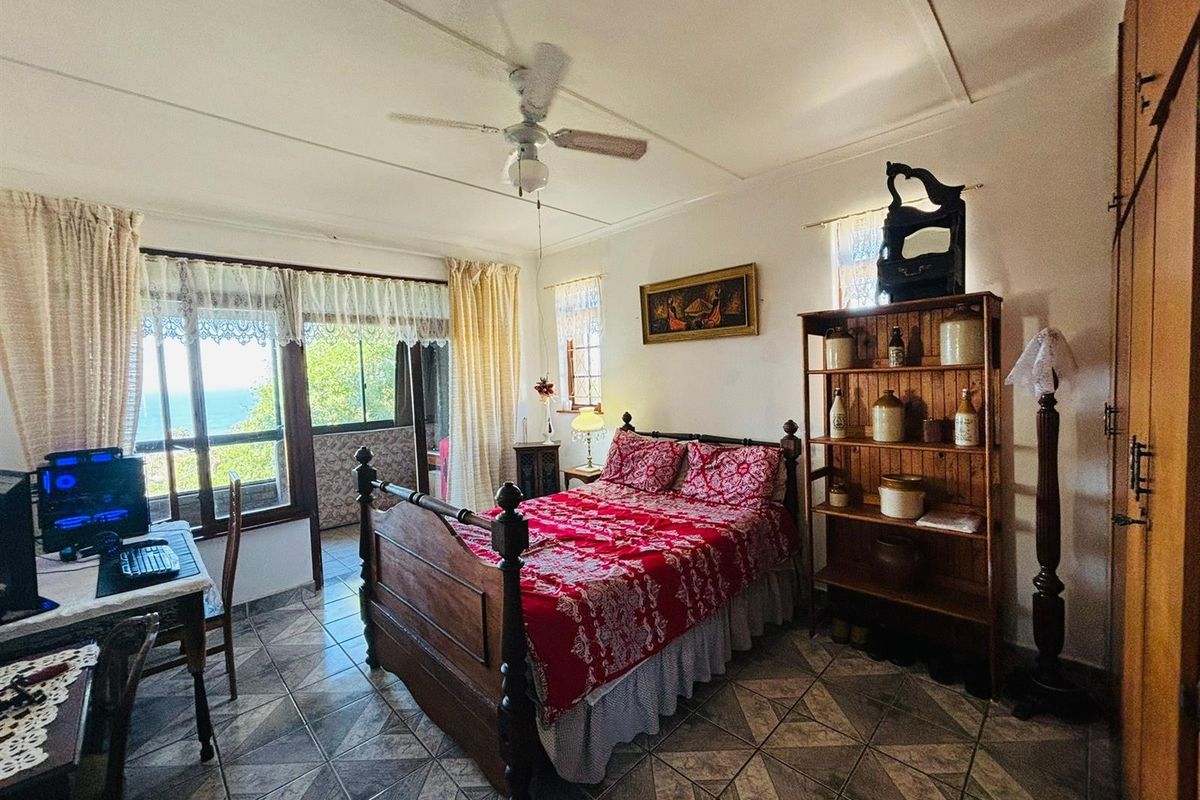 A bedroom featuring tiled flooring, a ceiling fan, and built-in wooden cabinetry, with direct access to an adjoining balcony offering scenic views.