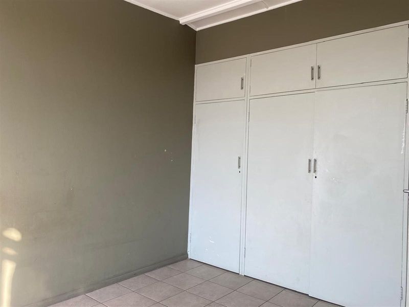 A bedroom featuring built-in cupboards with overhead storage and tiled flooring.