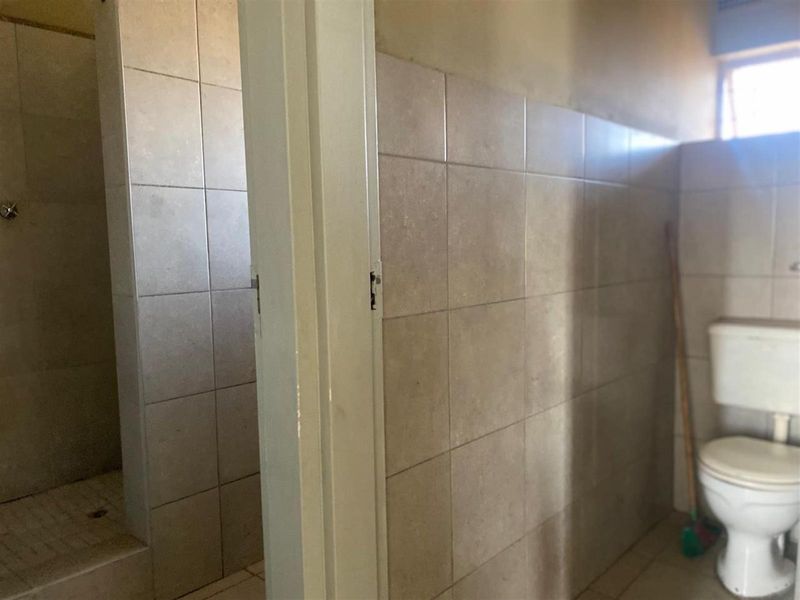 A functional bathroom featuring a tiled shower enclosure and a standard toilet, requiring some cosmetic updates to improve its overall condition.