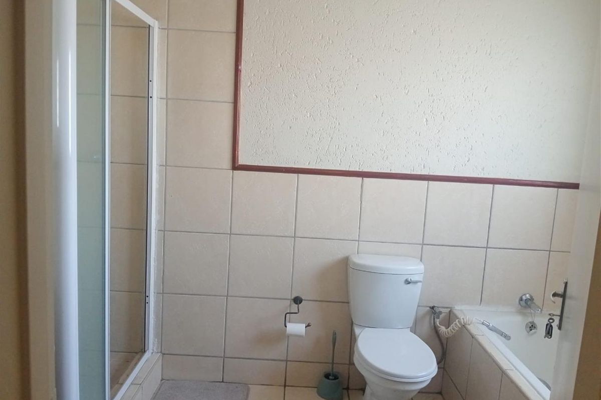 A functional bathroom featuring a tiled shower enclosure, a standard toilet, and a built-in bathtub with wall-mounted fixtures.