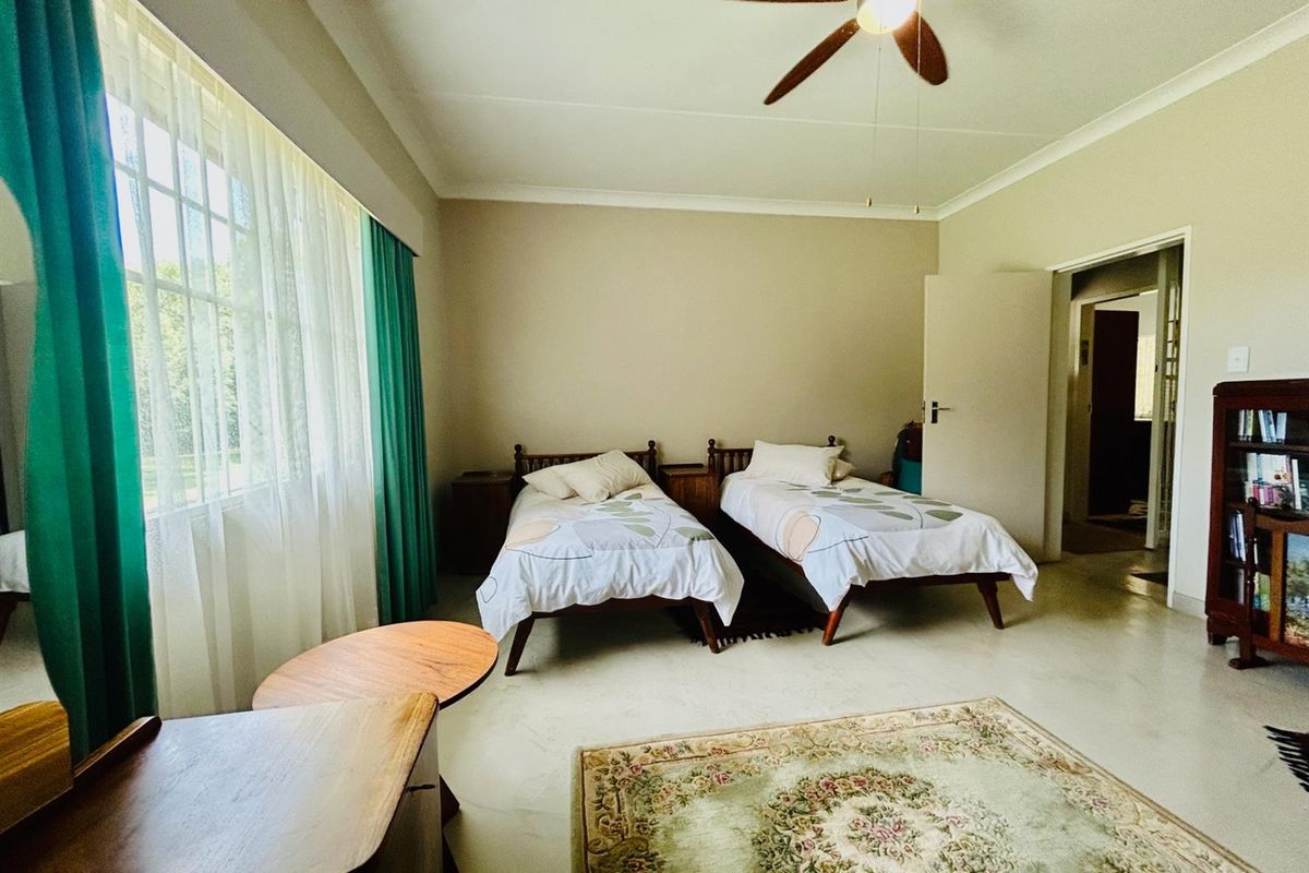 A spacious bedroom featuring tiled flooring, a ceiling fan, and large windows allowing for natural light.