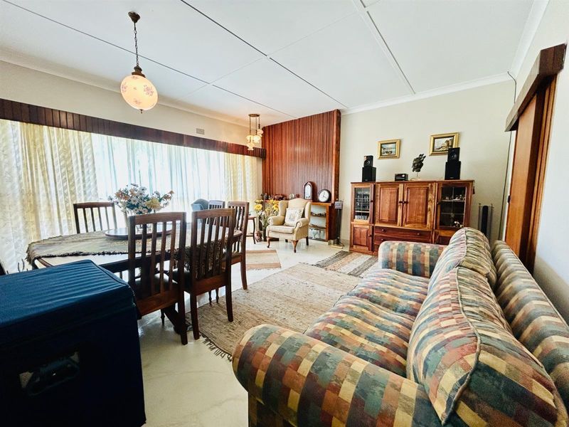Spacious open-plan living and dining area featuring tiled floors, a wood-paneled feature wall, and large sliding doors providing ample natural light.