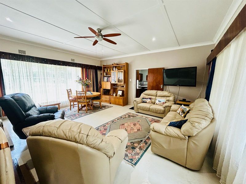 Spacious open-plan living and dining area featuring tiled flooring, a ceiling fan, and large sliding doors providing ample natural light.