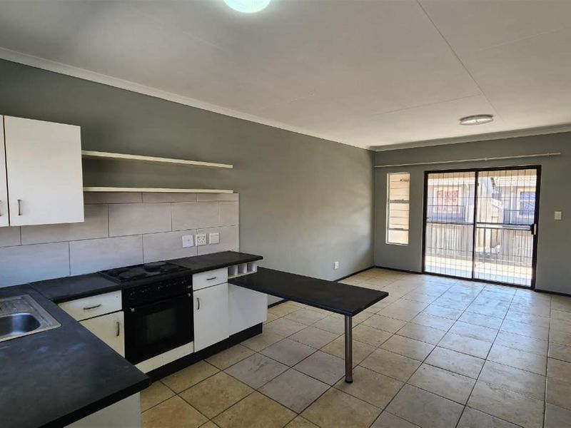 Open plan kitchen and living area featuring tiled flooring, built-in cabinetry, integrated stove, and sliding door access to a balcony.