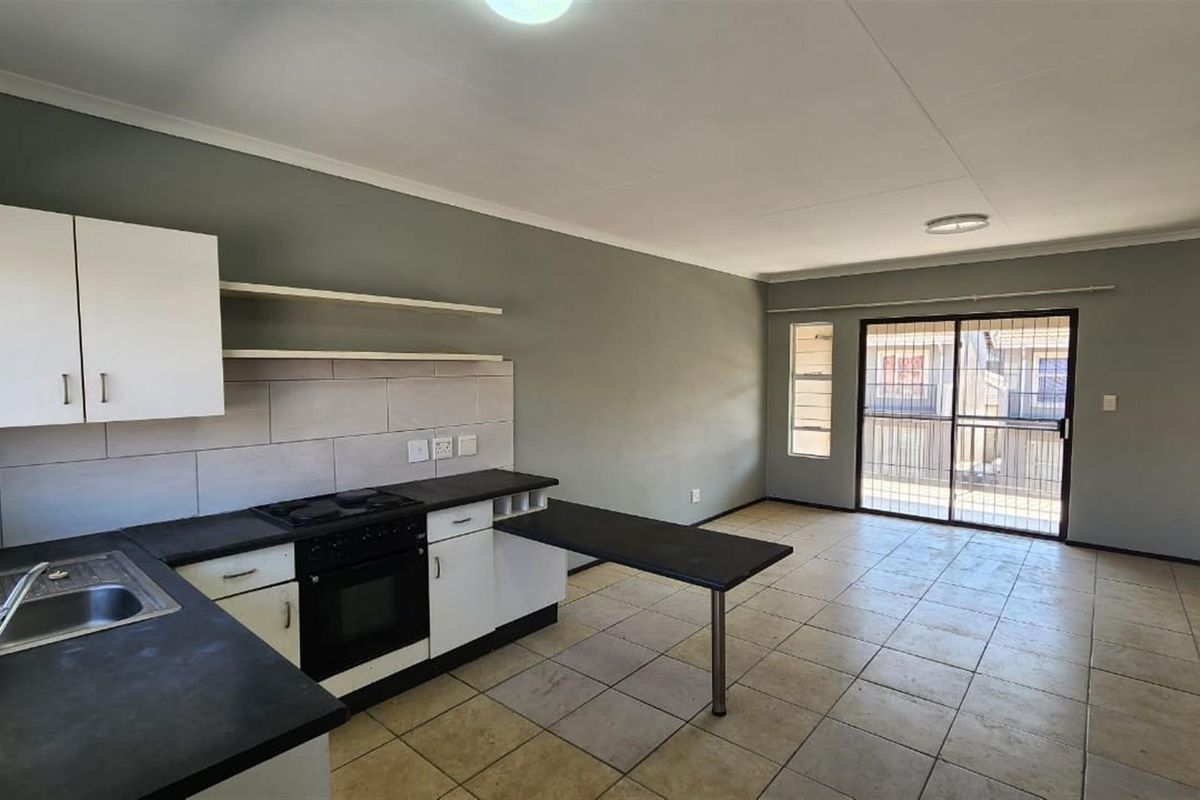 Open plan kitchen and living area featuring tiled flooring, built-in cabinetry, integrated stove, and sliding door access to a balcony.