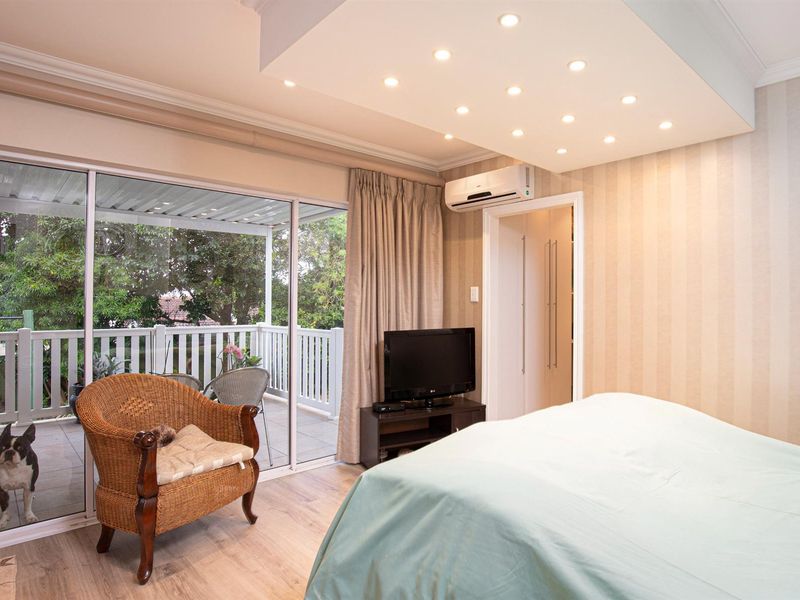 Spacious bedroom featuring recessed ceiling lighting, split-system air conditioning, and large sliding glass doors providing direct access to a private balcony.