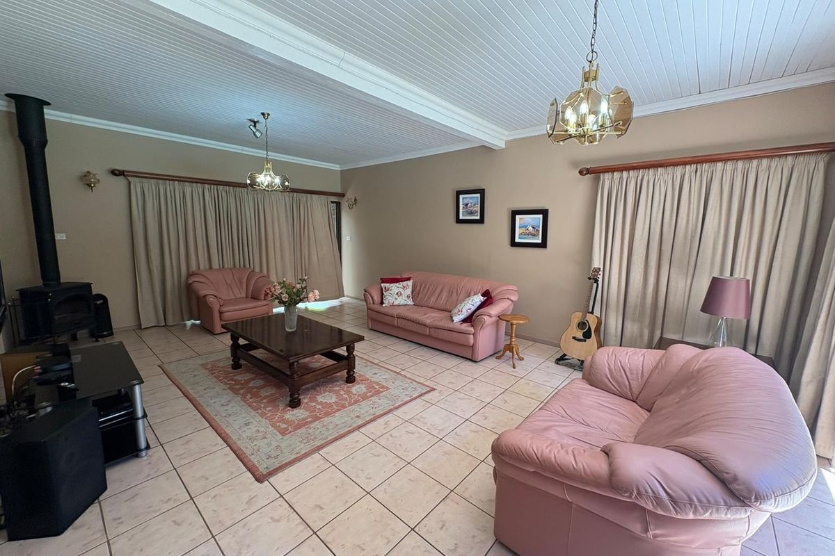 Spacious living room featuring tiled flooring, a wood-burning fireplace, and a vaulted tongue-and-groove ceiling with pendant lighting.