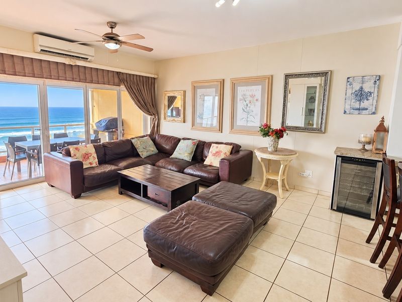 Spacious open-plan living area featuring tiled floors, air conditioning, and seamless access to a balcony with stunning ocean views.