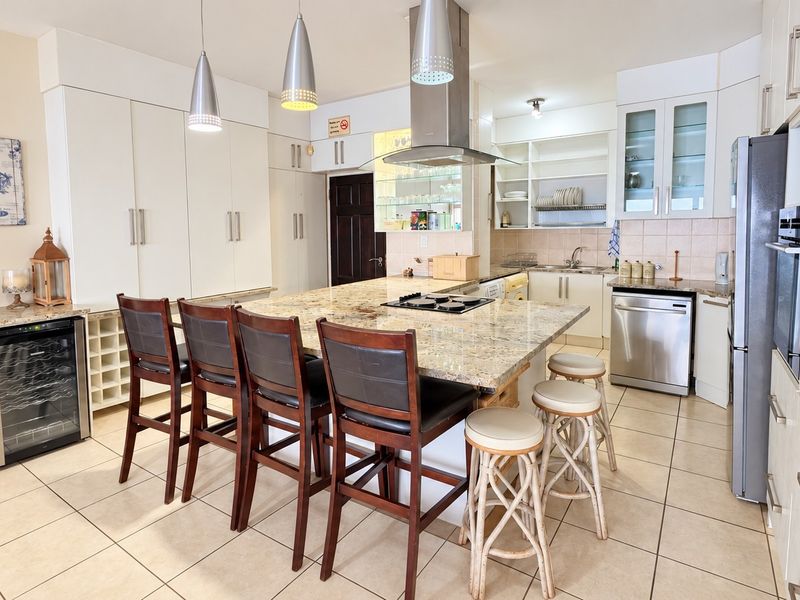 Spacious kitchen featuring a large granite-topped island, built-in cabinetry, integrated wine cooler, and stainless steel appliances, offering ample storage and workspace.