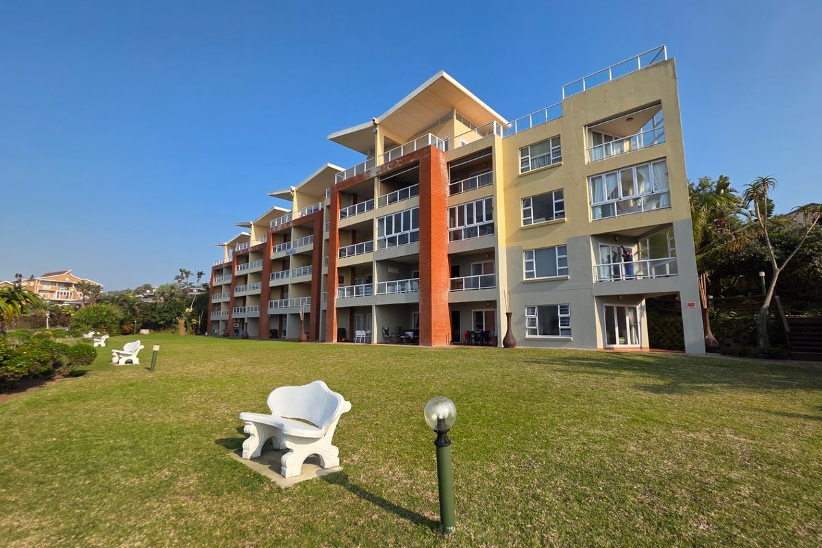 A view of the rear elevation of a multi-story apartment complex featuring private balconies and a well-maintained communal lawn area.