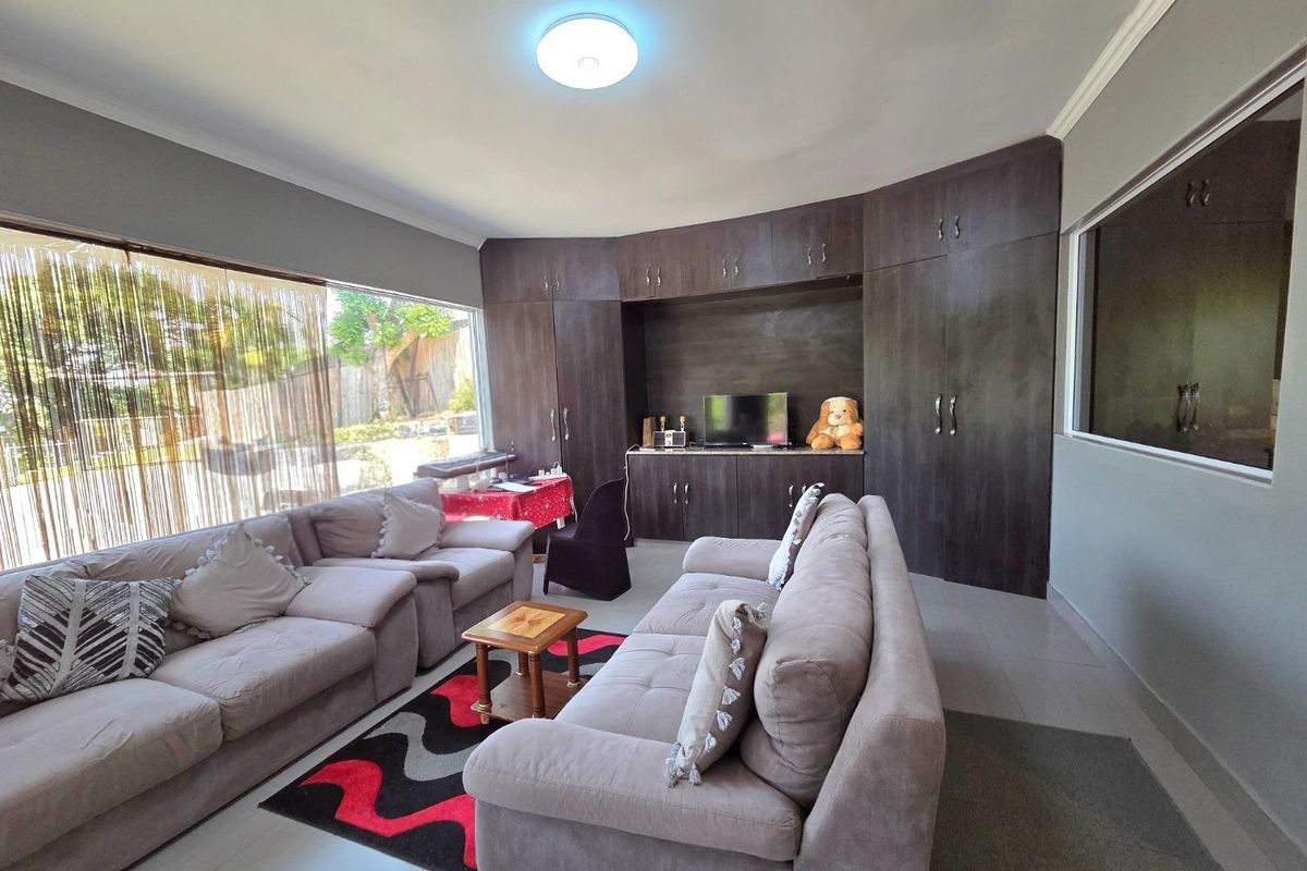 A spacious living room featuring extensive dark wood built-in cabinetry and large windows providing natural light.