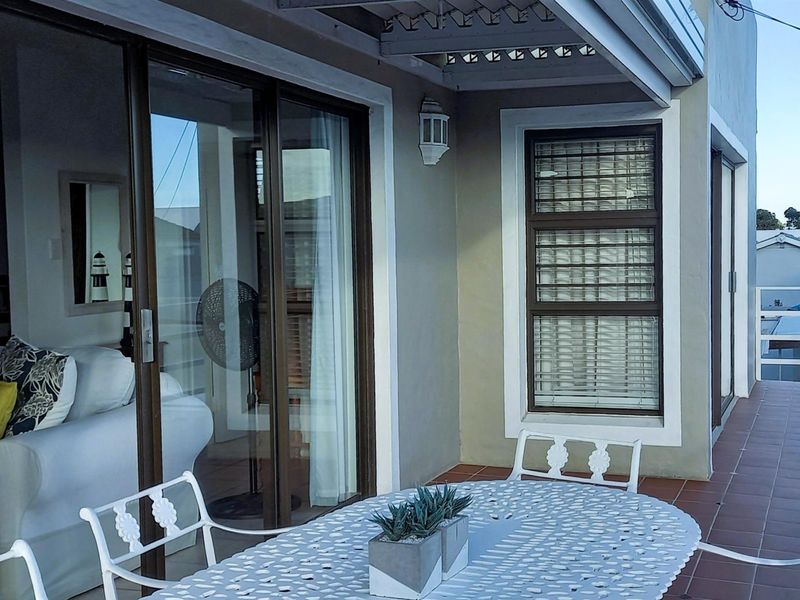 A covered patio area featuring tiled flooring, sliding glass doors leading to the interior, and a pergola structure.