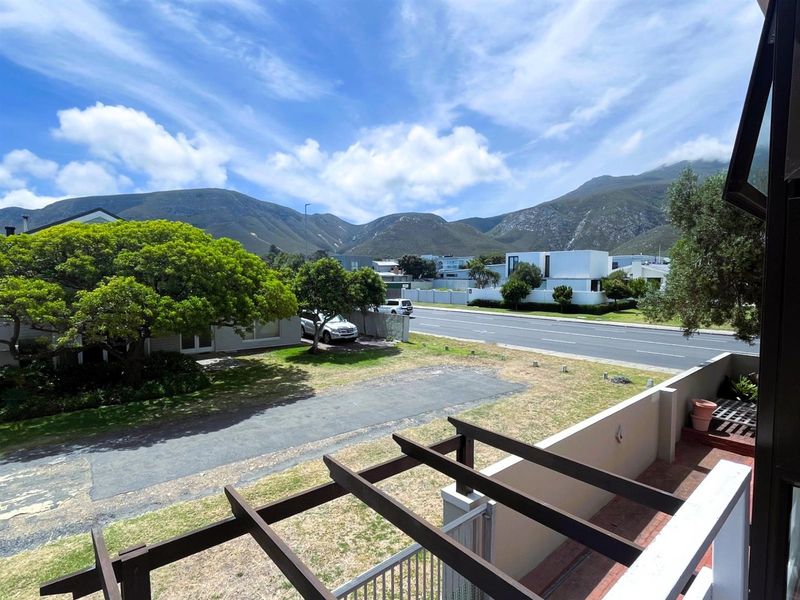 Elevated view overlooking the street, surrounding neighborhood, and scenic mountain range, featuring a wooden pergola structure in the foreground.