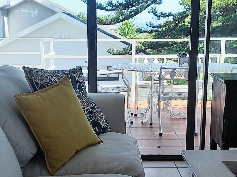A bright covered balcony featuring tiled flooring and sliding glass doors, offering a seamless transition to the outdoor entertainment area.
