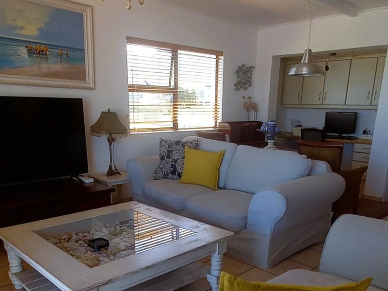 Open plan living area featuring tiled floors, beamed ceilings, and a connected workspace with built-in cabinetry.