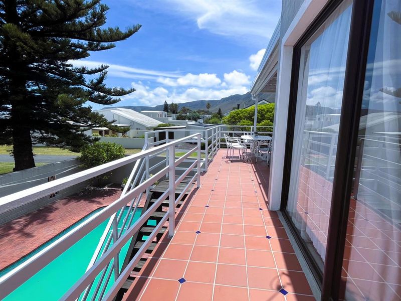 Spacious elevated balcony featuring tiled flooring, a secure metal balustrade, and direct access to the pool area via an external staircase.