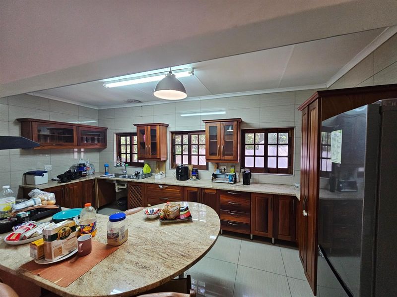 Spacious kitchen featuring solid wood cabinetry, granite countertops, tiled flooring, and multiple windows providing natural light.