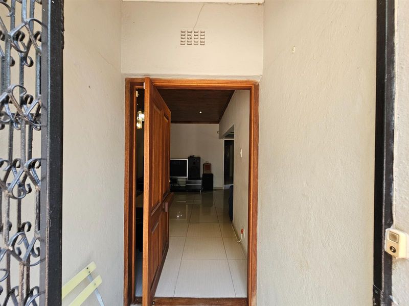 View through the main entrance door into the interior living space, featuring tiled flooring and a timber-paneled ceiling.