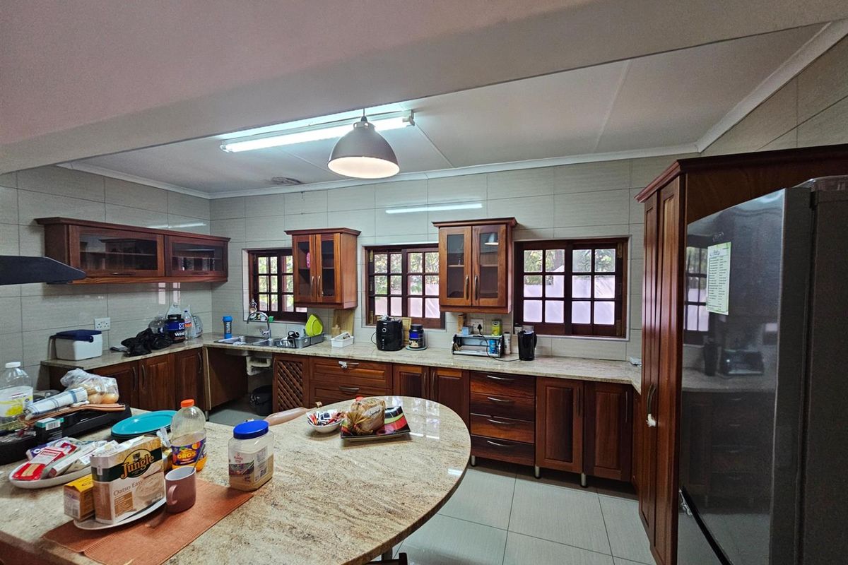 Spacious kitchen featuring solid wood cabinetry, granite countertops, tiled flooring, and multiple windows providing natural light.