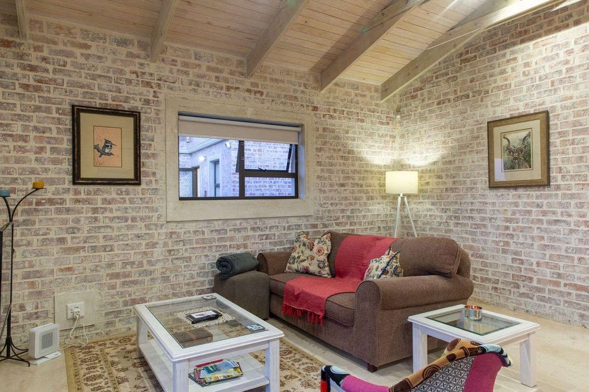 A cozy living room featuring rustic exposed brick walls and a vaulted timber beam ceiling, creating a warm and character-filled atmosphere.