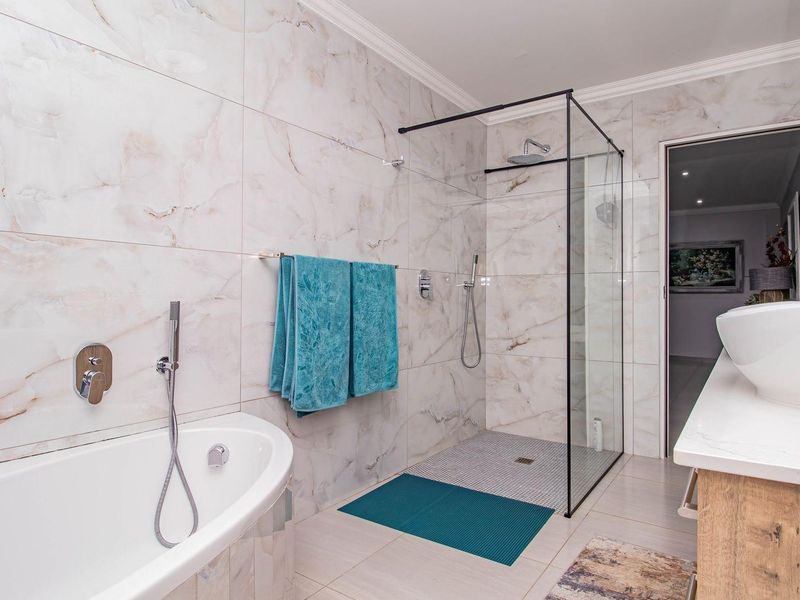 Modern bathroom featuring a freestanding bathtub, a walk-in glass shower with black frame, and a vanity with a vessel sink.