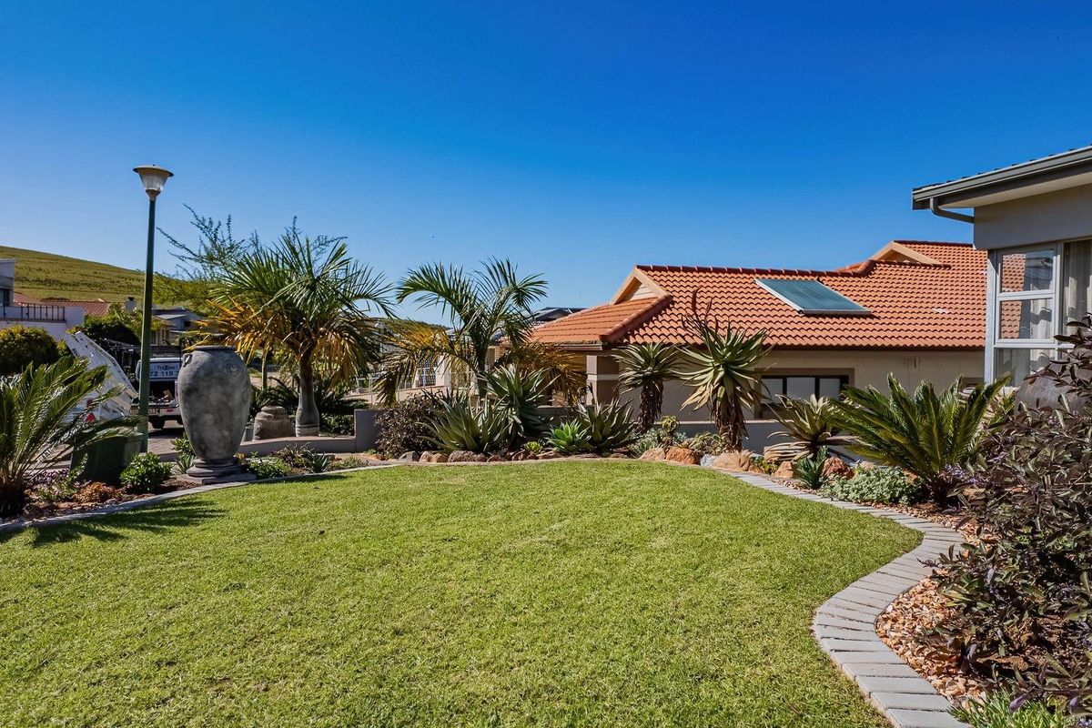 A well-maintained rear garden featuring a manicured lawn, paved edging, and established landscaping with a view of the house exterior.