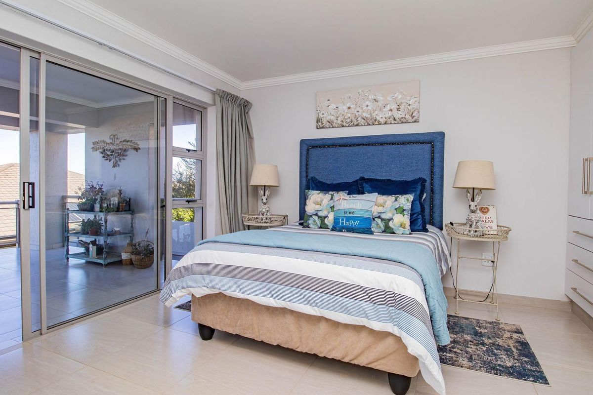 A bright bedroom featuring built-in cupboards, tiled flooring, and large sliding glass doors that open onto a private balcony.