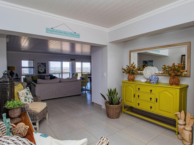 An inviting entrance hall featuring tiled flooring and tongue-and-groove ceiling detail, flowing seamlessly into an open-plan living area with expansive views.