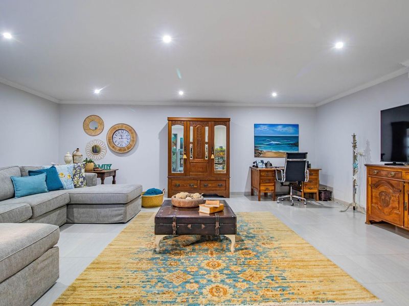 Spacious living room featuring recessed downlighting, neutral tiled flooring, and a clean, open-plan layout suitable for versatile furniture arrangements.
