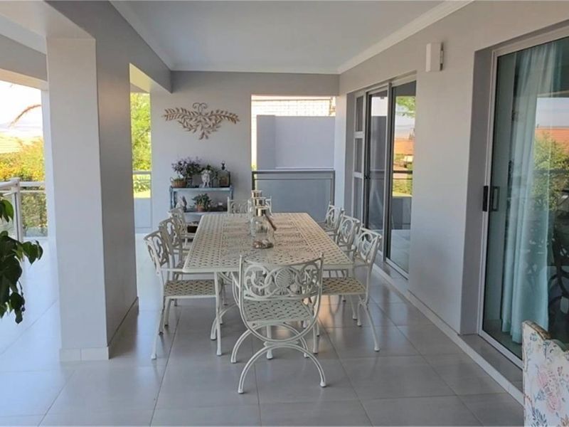 A spacious covered patio featuring tiled flooring and large sliding glass doors, providing a seamless transition between indoor and outdoor living areas.