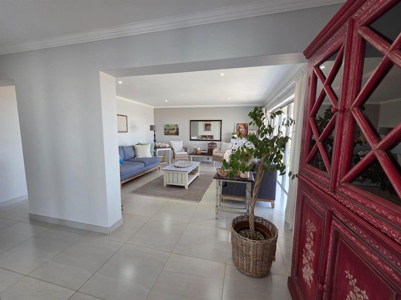Spacious open-plan living area featuring neutral tiled flooring, recessed downlighting, and large sliding glass doors providing ample natural light and access to the outdoors.