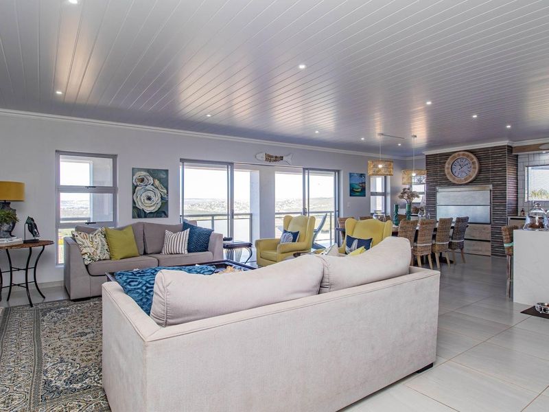 Spacious open-plan living area featuring a modern kitchen with a stone island, recessed lighting, and large sliding doors leading to a balcony.