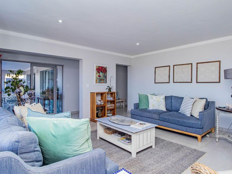 A bright and spacious living room featuring tiled flooring, recessed lighting, and large sliding glass doors leading to an adjacent patio area.