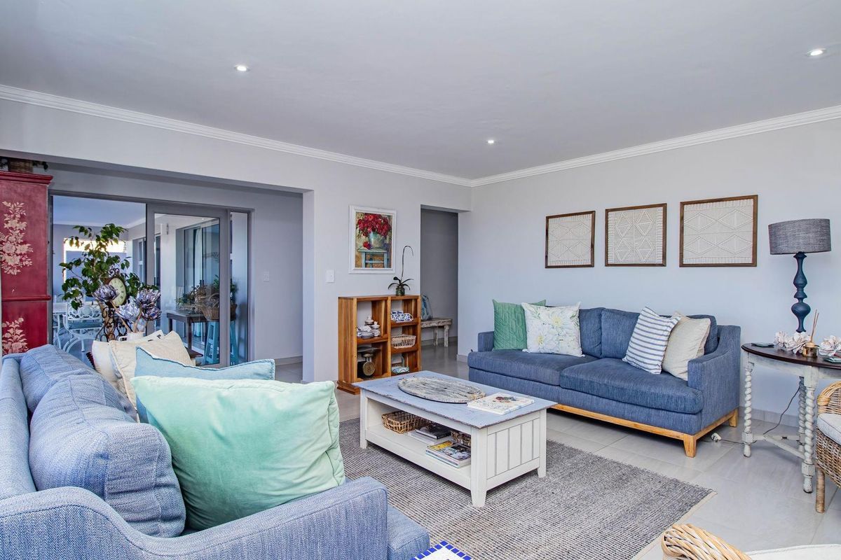 A bright and spacious living room featuring tiled flooring, recessed lighting, and large sliding glass doors leading to an adjacent patio area.
