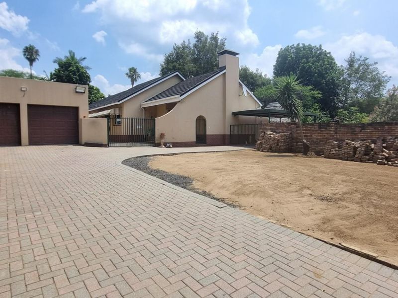 Front exterior view of the property featuring a paved driveway, double garage, and a large garden area currently undergoing landscaping.