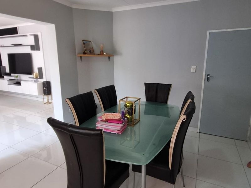 Open plan dining area featuring neutral wall tones and polished tiled flooring, seamlessly connecting to the adjacent living space.