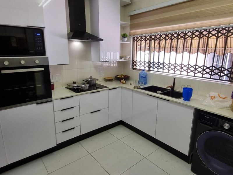 Modern kitchen featuring white cabinetry, built-in oven and microwave, extractor fan, hob, and a double sink with tiled flooring.