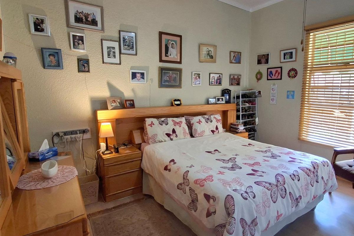 A well-maintained bedroom featuring a built-in wooden headboard with integrated bedside tables and wooden window blinds.