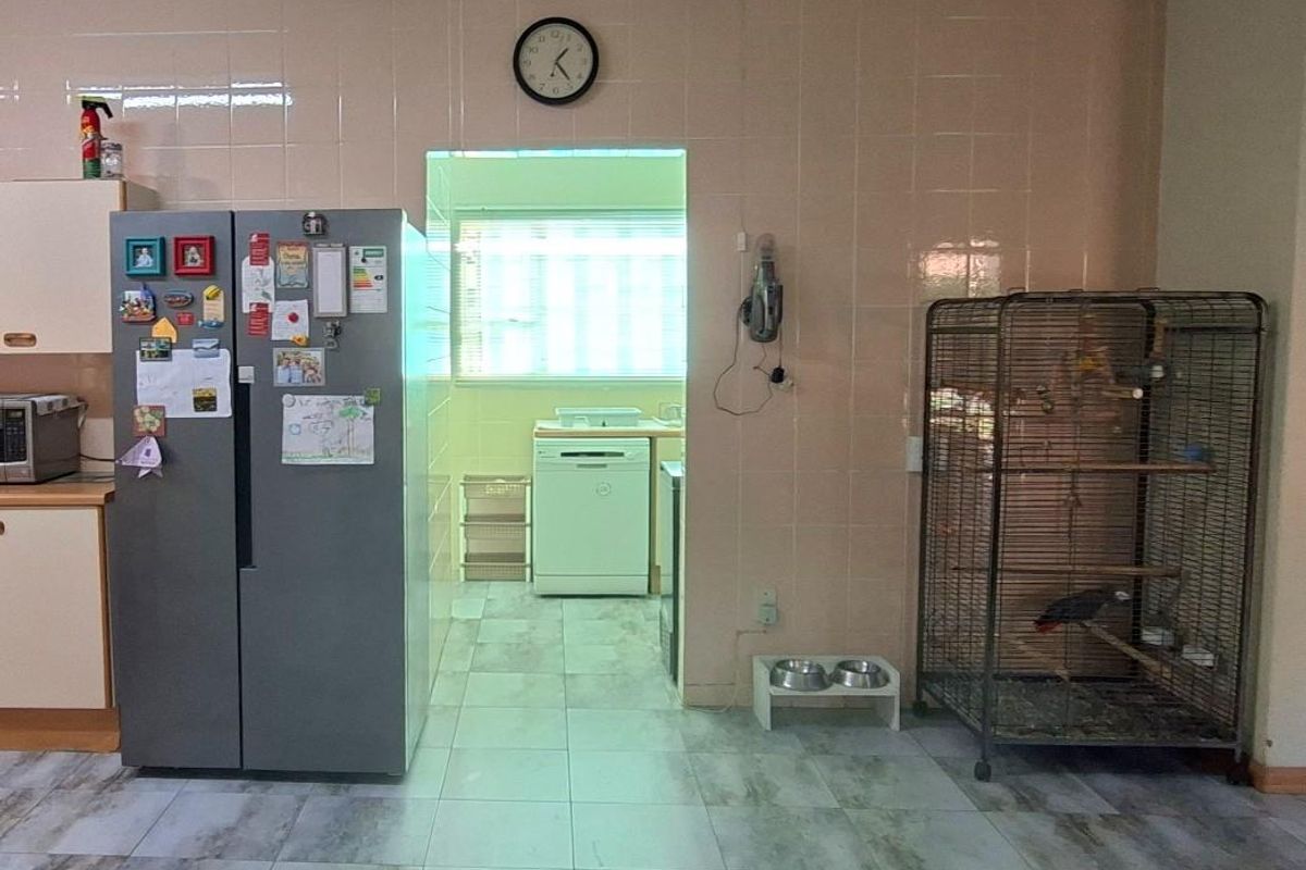 A functional kitchen area featuring tiled walls and flooring, with a connected scullery space visible through the doorway.