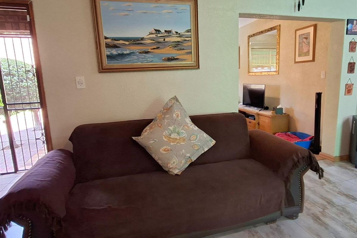 A living area featuring tiled flooring and a security gate leading to the exterior, with an open transition to an adjacent room.