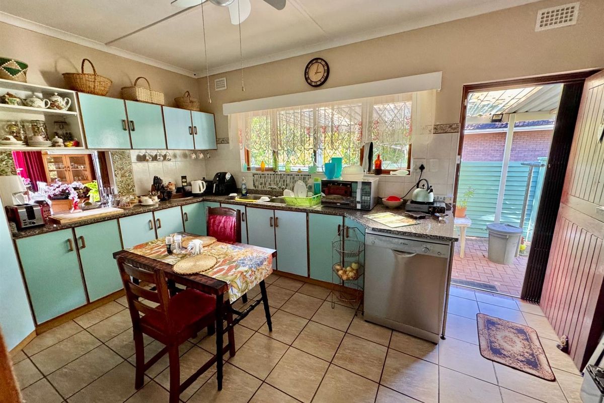 A functional kitchen featuring light blue cabinetry, tiled flooring, and direct access to an outdoor patio area.