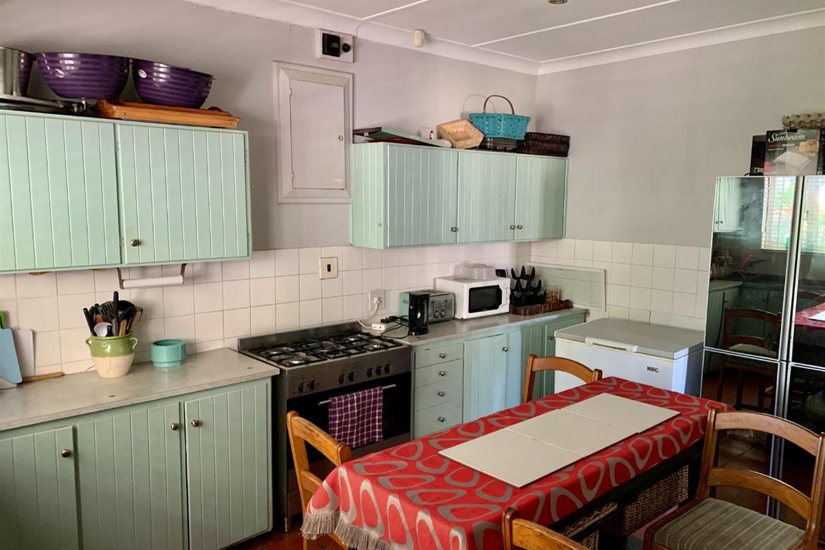 A functional kitchen featuring mint-green cabinetry, a gas hob with oven, and tiled splashbacks, offering a practical layout for daily meal preparation.