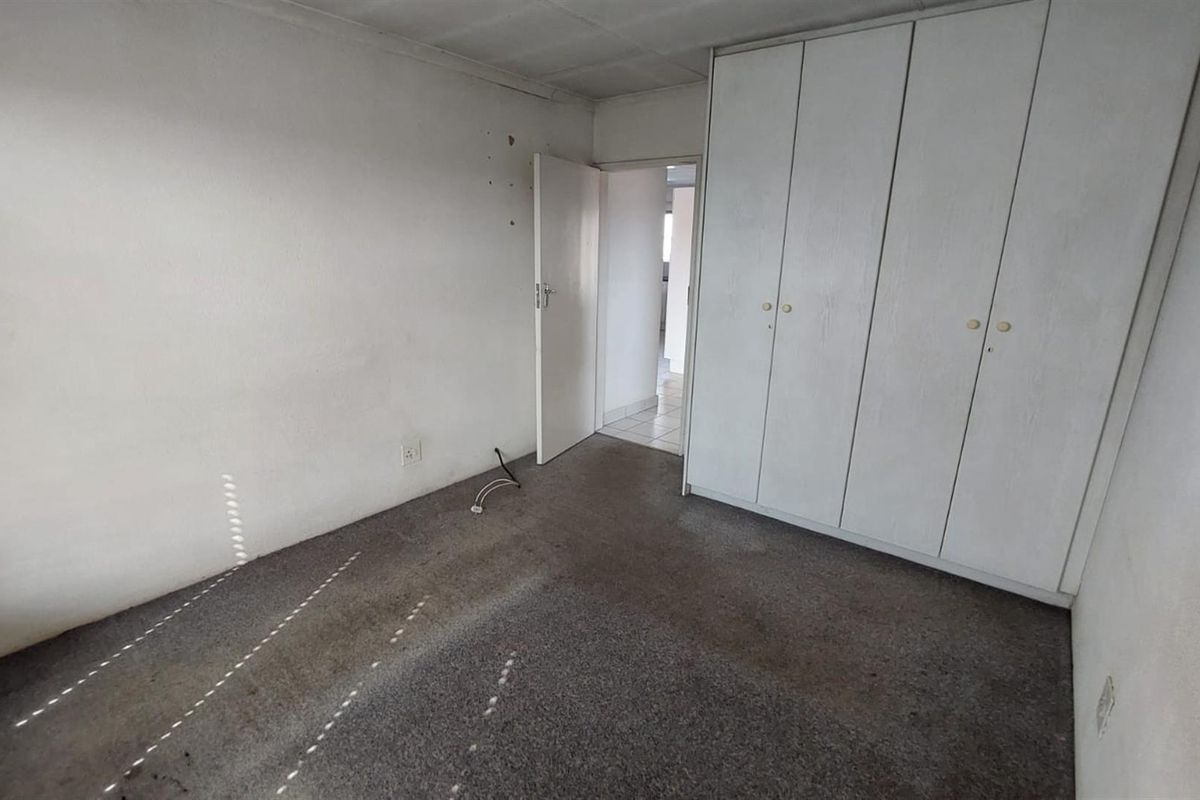 An empty bedroom featuring built-in cupboards and carpeted flooring, requiring cosmetic updates to improve its overall condition and appeal.