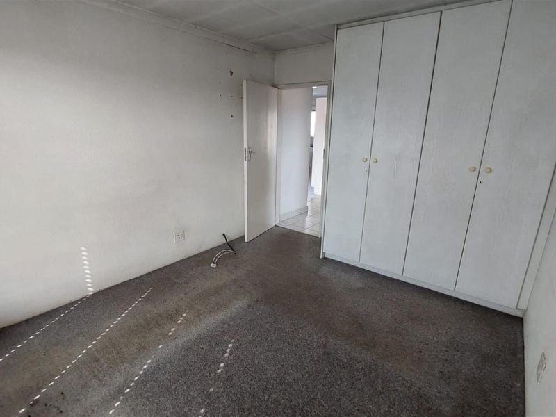 An empty bedroom featuring built-in cupboards and carpeted flooring, requiring cosmetic updates to improve its overall condition and appeal.