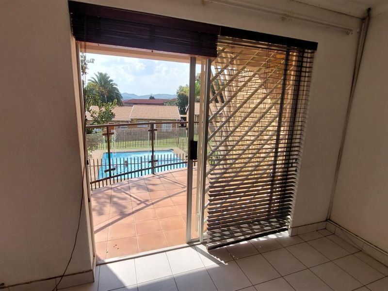 An interior view looking out through a sliding glass door onto a tiled patio area with a pool view.
