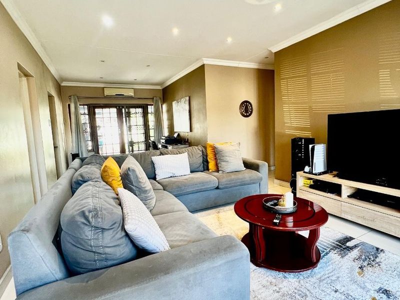 Spacious living room featuring tiled flooring, recessed downlighting, and a split-system air conditioner, with direct access to an outdoor area through sliding glass doors.