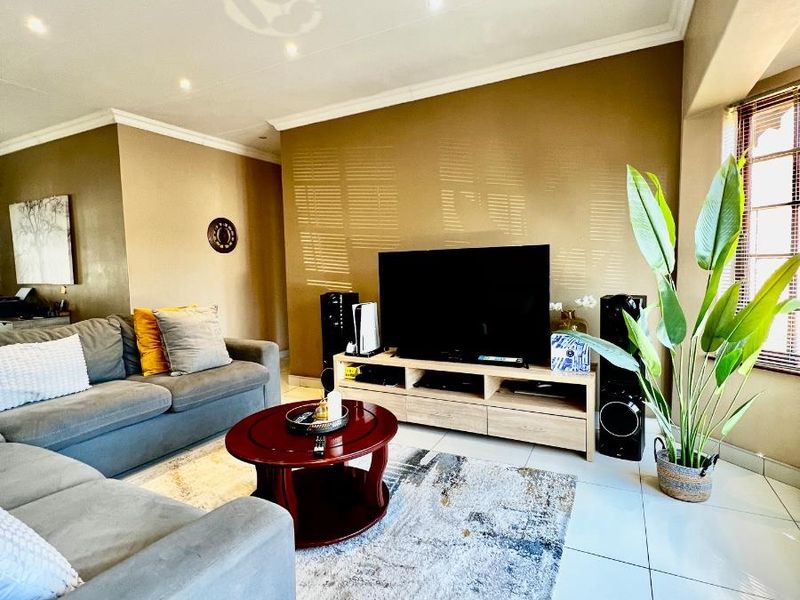 A comfortable living room featuring tiled flooring, recessed downlighting, and venetian blinds, providing a neutral and functional space for relaxation.