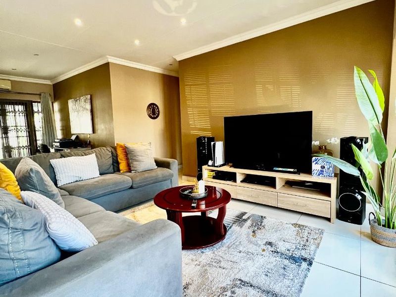 A well-maintained living room featuring neutral tiled flooring, recessed downlighting, and coved cornicing, creating a comfortable and functional space.