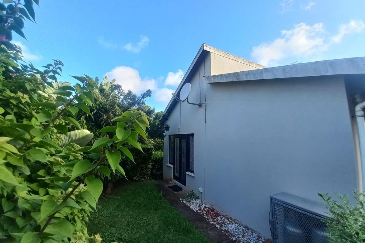 Rear view of the cottage featuring a garden area, exterior wall with satellite dish, and access via french doors.